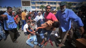 A Palestinian man carries an injured child following an Israeli military strike on a UN school in Rafah, in the southern Gaza Strip on August 3, 2014. [PressTV Photo]